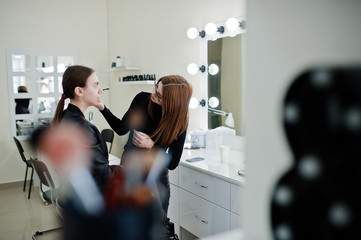 Make up artist work in her beauty visage studio salon. Woman applying by professional make up...