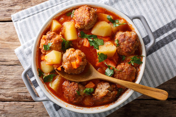 Meatballs tomato soup with vegetables and herbs close-up in a bowl on the table. horizontal top view from above