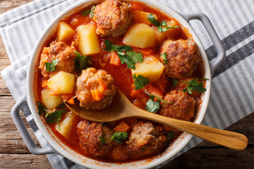Freshly made tomato soup with meatballs and vegetables close-up in a pot. Horizontal top view
