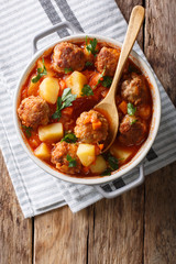 Hot stew meatball soup with vegetables in tomato sauce closeup in a pot. Vertical top view