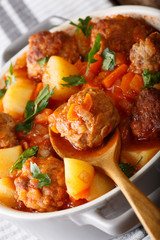 Meatballs tomato soup with vegetables and herbs close-up in a bowl. vertical
