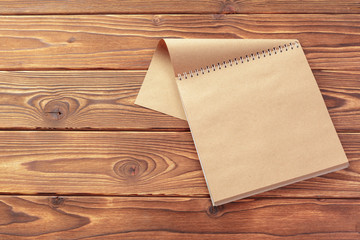 Office desk table top view. Notepad with blank pages on wooden table