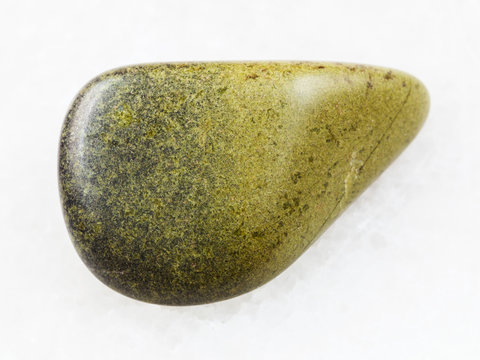 polished epidote gemstone on white marble