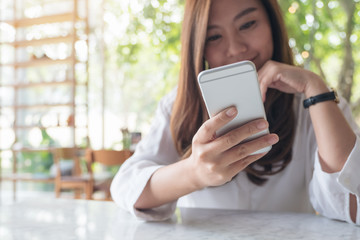 Closeup image of a beautiful Asian woman holding , using and looking at smart phone with feeling happy