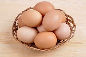 chicken eggs in a basket on a wooden background.