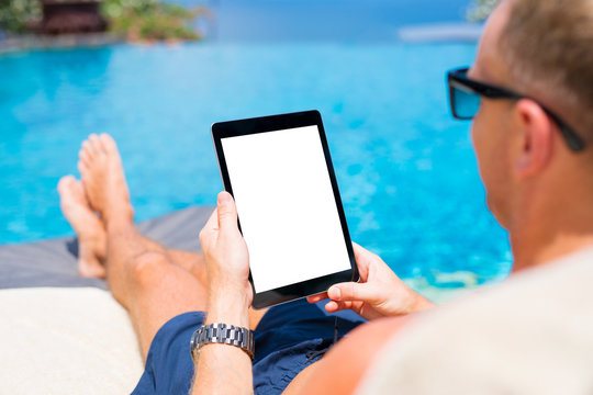 Man using tablet by the pool, blank white mock up screen