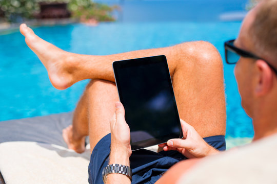 Man using tablet by the pool