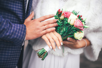 details of the wedding, the hands of the bride and groom with a ring and a beautiful tender bouquet, happy newlyweds
