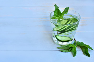 Cucumber detoxing water in a glass, left copy space.