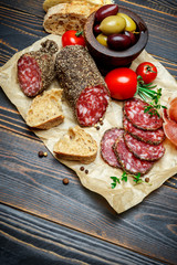 Dried organic salami sausage covered with pepper on wooden background