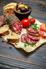 Dried organic salami sausage covered with pepper on wooden background