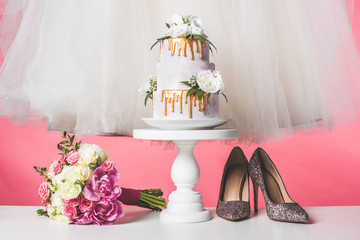 pair of shoes, wedding bouquet, cake and white dress isolated on pink
