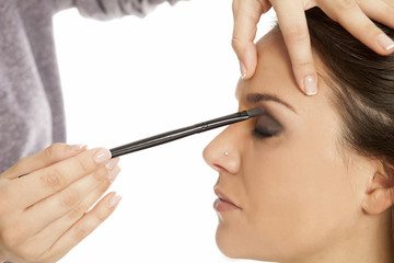Makeup artist applying eyeshadow with brush on white background