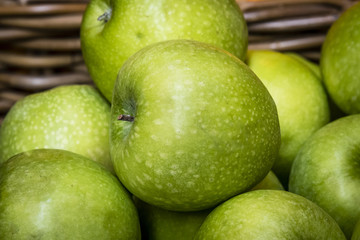 Closeup of green apples in wicker basket. Delicious fresh green juicy apples in local fruit market.