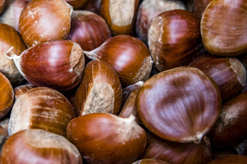 Pile of brown chestnuts, food background. Big pile of fresh raw chestnuts ready for roasting.