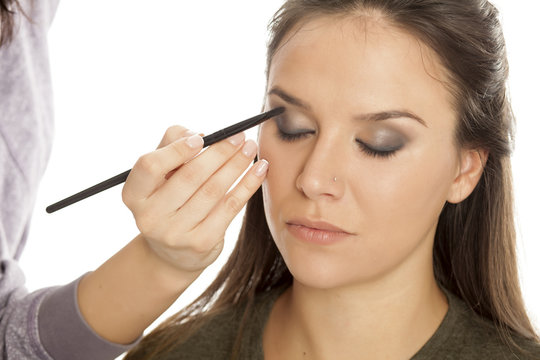 Makeup artist applying eyeshadow with brush on white background