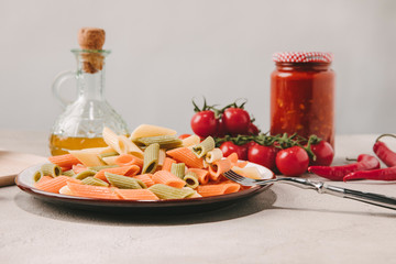 colorful pasta on plate with various food on background on concrete surface