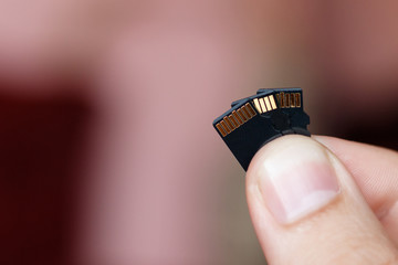 Micro sd card in human fingers on brown background with copy space