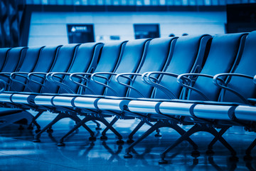 row of empty blue seats in airport lobby,blue toned,china.
