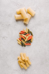 top view of piles of different raw pasta in row on concrete surface