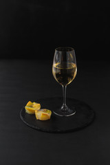 a glass of white wine on a black table with a fruit dessert