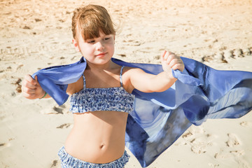 Little Caucasian girl plays with blue shawl