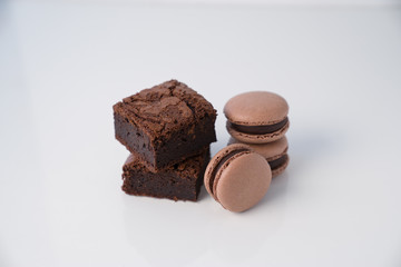 Brownie and macaroons ctacked on white background