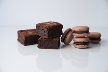 Brownie and macaroons ctacked on white background