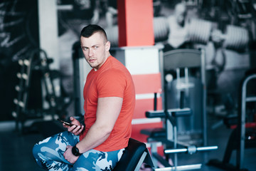 Fototapeta na wymiar Handsome athletic man in gym, use mobile phone, surfing internet social network.
