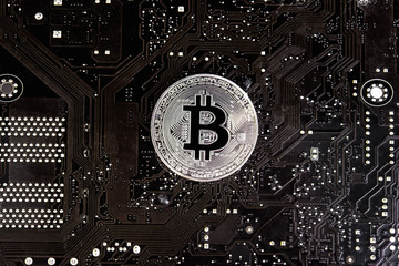 Bitcoin coin isolated on a circuit board black background. Silver coin, virtual currency. Crypto currency. New virtual money of the future.