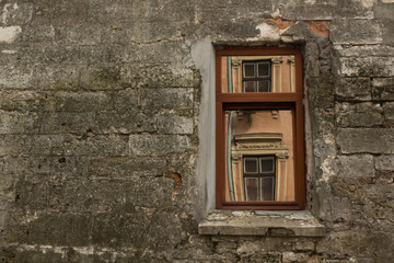 Fototapeta na wymiar Beauty in reflection concept with window in old slum concrete wall in backstreet