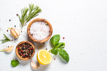 Spices and herbs over white stone table top view.