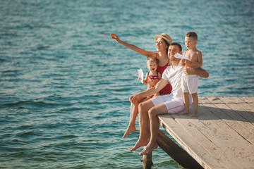 Happy cheerful family at the pier near the water having fun. Adorable kids playing with their parents