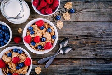 A healthy breakfast bowl. Whole grain cereal with fresh blueberries and raspberries on wooden background. Top view