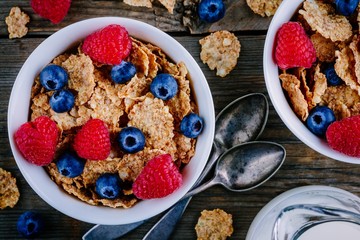 A healthy breakfast bowl. Whole grain cereal with fresh blueberries and raspberries on wooden background. Top view