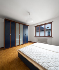 Bedroom with parquet, bed without blankets