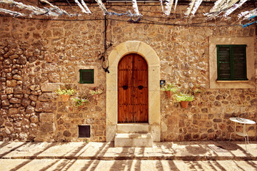 Fototapeta na wymiar Detail of old door gateway and a window in Mallorca with flower decoration on sides