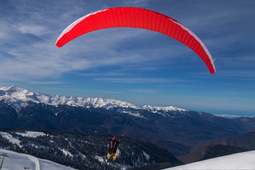 The snowboarders, skiers in action at the mountains.Paraglider with an instructor.