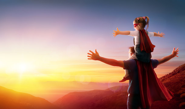 Daughter And Her Father Dressed As Heroes Watching The Sunset
