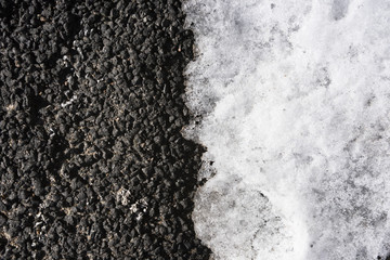 Background of dark asphalt with light snow in half from above