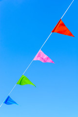 Four colorful party flags blowing in the wind against blue sky.