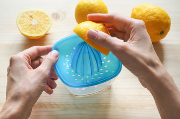 Hand squeezer with lemons on wooden background.
