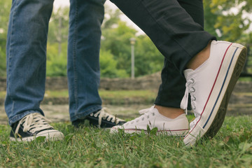 Couple in love standing in nature. Canvas shoes in focus.