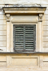 Fototapeta na wymiar Window closed with old, wooden blinds on an old European building
