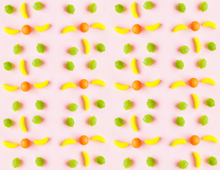 Food pattern of sweet toys in the form of fruit, banana, lemon, strawberry, orange, abstract pink and purple background 