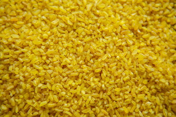 Croup of bulgur placer, pile. The product is rich in protein, healthy food, vegetarianism. Yellow and brown. View from above. Close up