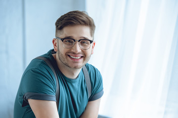 portrait of handsme young man in eyeglasses smiling at camera