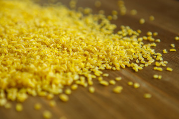 Croup of bulgur placer, pile on a wooden brown background. The product is rich in protein, healthy...
