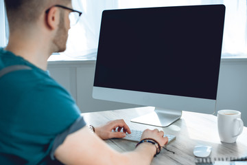 cropped shot of young freelancer using desktop computer with blank screen