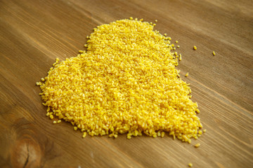 Croup of bulgur placer, a pile on a wooden brown background is lined in the form of a symbol of the...